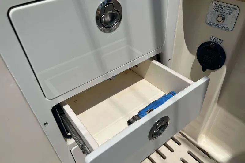 Slide: The Image of Open storage drawer on 2021 Scout 305 LXF boat, featuring a blue tool inside. - 20