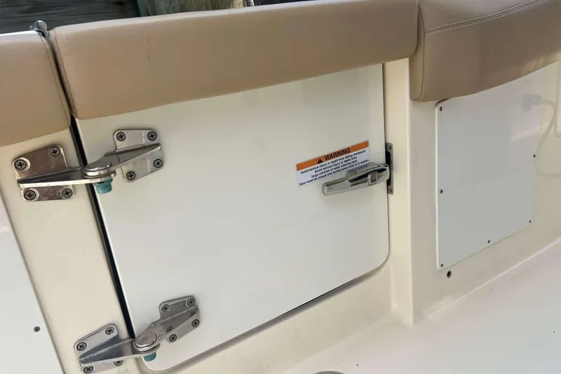 Slide: The Image of 2021 Scout 305 LXF boat compartment with secure latches and warning label. - 21