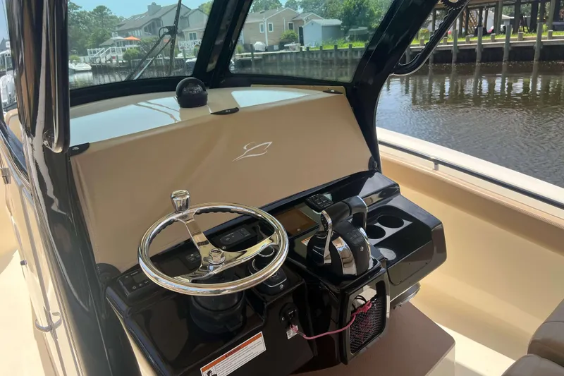 Slide: The Image of 2021 Scout 305 LXF boat helm with steering wheel and controls, dockside view. - 26