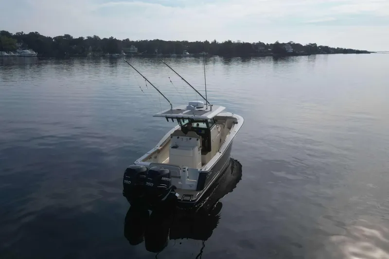 Slide: The Image of 2021 Scout 305 LXF boat on calm water with dual engines and fishing rods. - 3