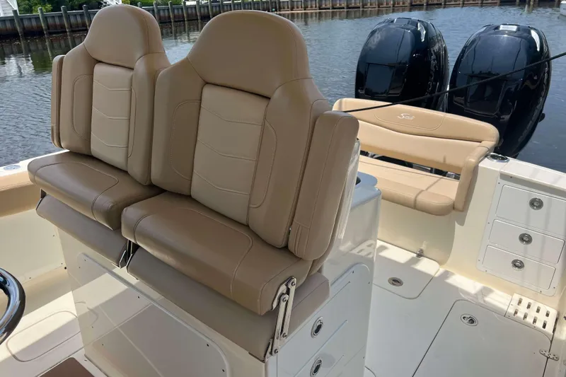 Slide: The Image of 2021 Scout 305 LXF boat interior with tan seating and dual engines. - 30