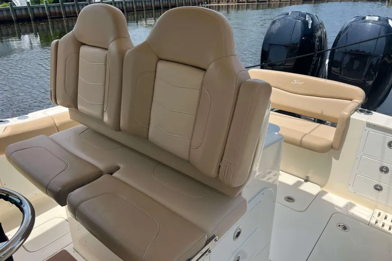 Slide: The Image of 2021 Scout 305 LXF boat interior with beige seating and dual outboard engines. - 31