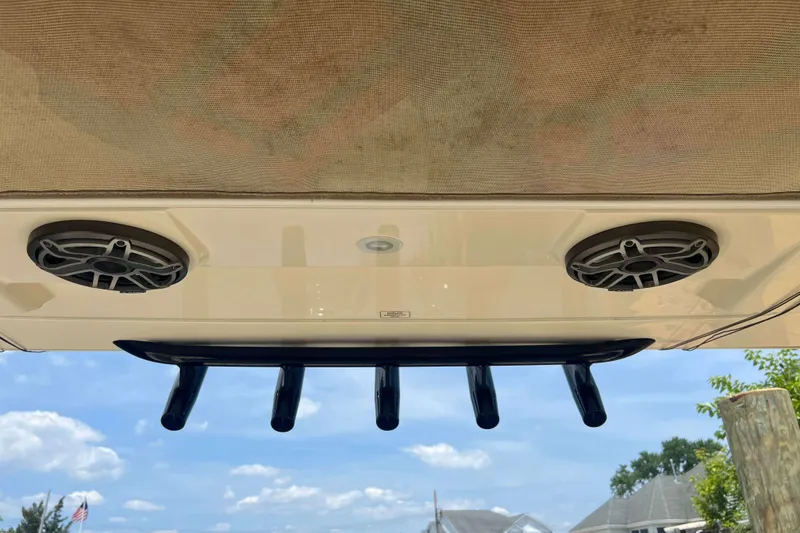 Slide: The Image of 2021 Scout 305 LXF boat speakers and rod holders under canopy, clear sky background. - 33