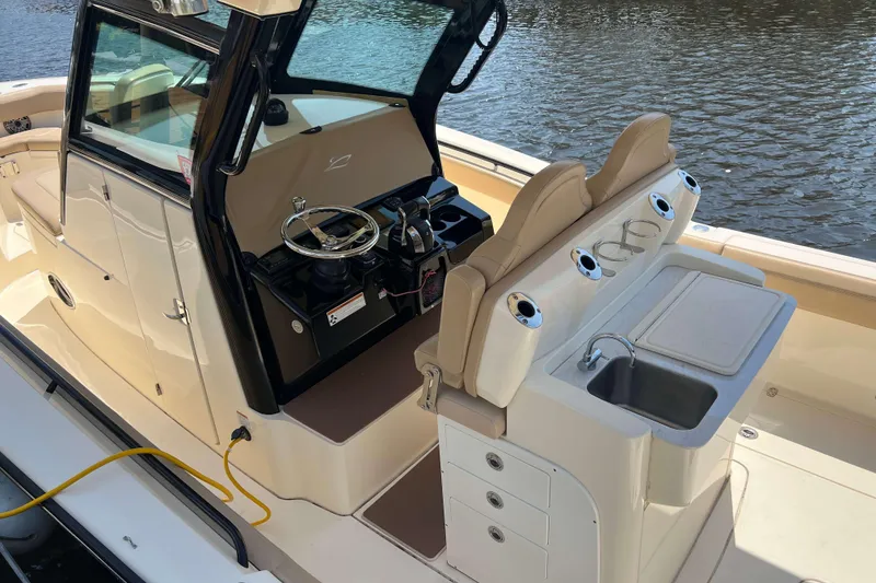 Slide: The Image of 2021 Scout 305 LXF boat interior with helm, seating, and sink by the water. - 4