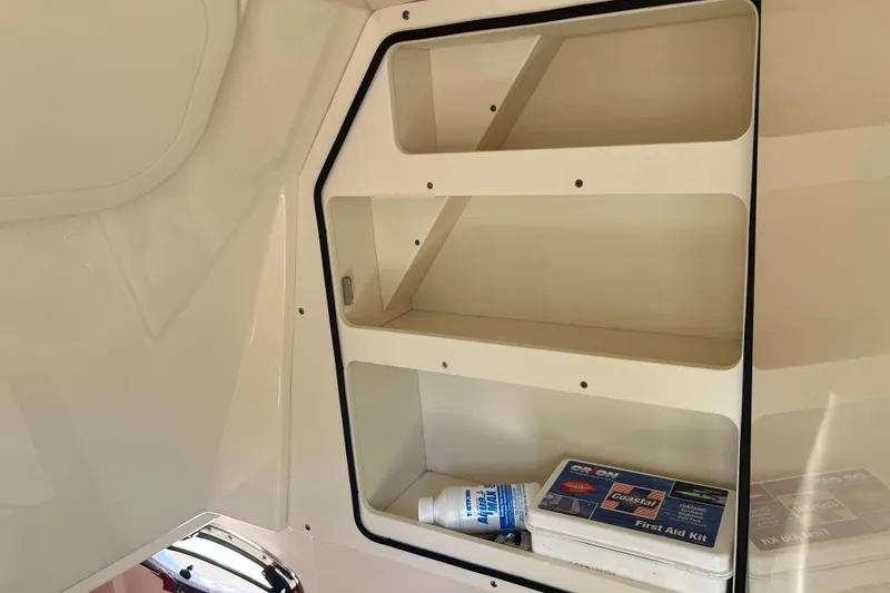 Slide: The Image of 2021 Scout 305 LXF boat interior storage with first aid kit and sunscreen. - 46