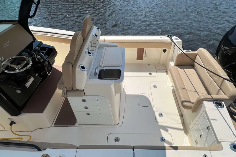Slide: The Image of 2021 Scout 305 LXF boat interior with helm, seating, and sink, on water. - 5