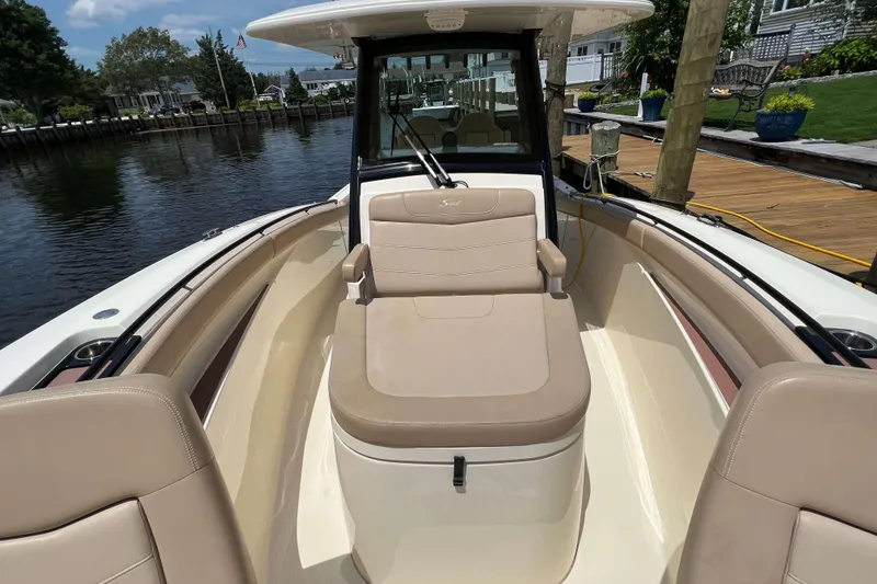Slide: The Image of 2021 Scout 305 LXF boat interior with beige seating and waterfront view. - 59