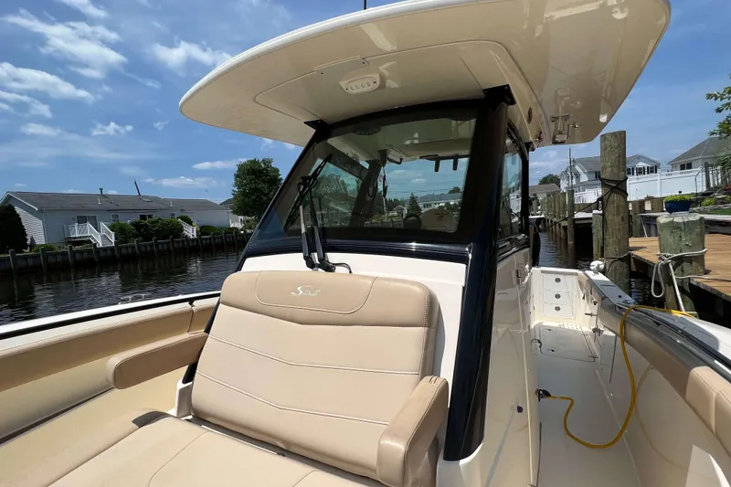 Slide: The Image of 2021 Scout 305 LXF boat docked, featuring beige seating and sleek design. - 60