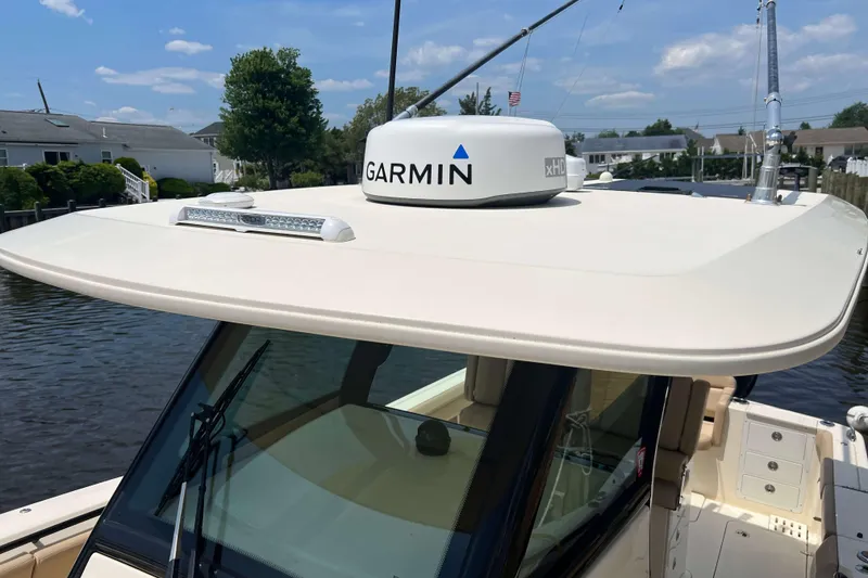 Slide: The Image of 2021 Scout 305 LXF boat with Garmin radar on top, docked by waterfront homes. - 62