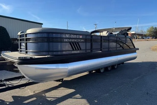 Slide: The Image of 2022 Bennington 23LFB pontoon boat on trailer, parked outdoors under clear blue sky. - 4