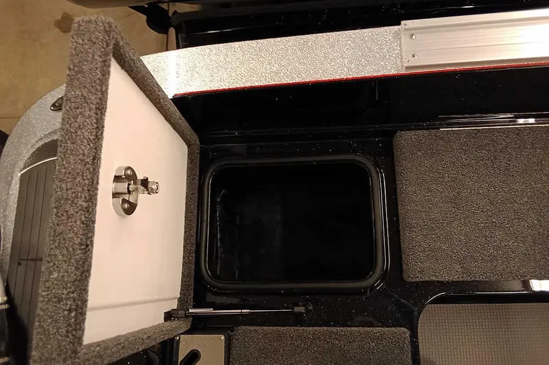 Slide: The Image of Open storage compartment in 2026 Ranger 621FS Fisherman boat, featuring carpeted interior and secure latch. - 26