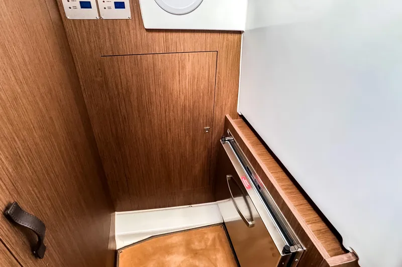 Slide: The Image of Interior of 2022 Beneteau Antares 11 Fly, featuring wood paneling and compact storage. - 23
