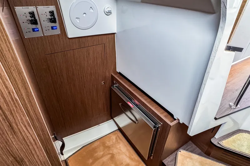 Slide: The Image of Interior of 2022 Beneteau Antares 11 Fly, featuring wood paneling and compact fridge. - 25