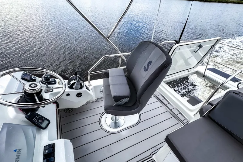 Slide: The Image of Flybridge of 2022 Beneteau Antares 11 Fly, featuring helm and seating, on calm water. - 40