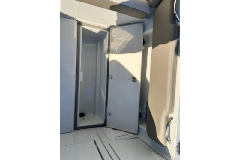 Slide: The Image of 2022 Finseeker 280 DC boat interior storage compartment with open door. - 14
