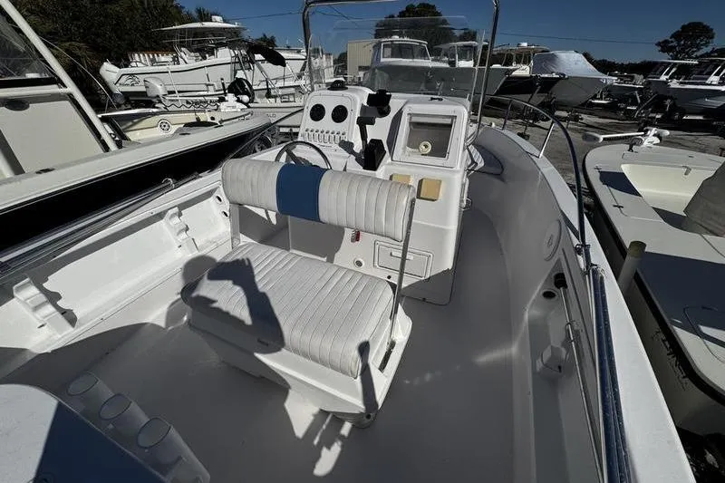 Slide: The Image of 2002 Pro-Line 19 Sport boat interior with steering console and seating, docked among other boats. - 14
