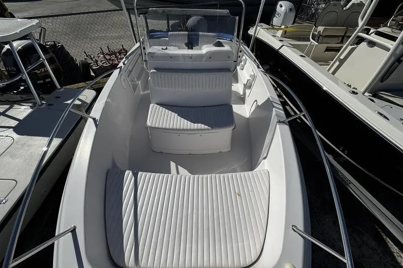 Slide: The Image of 2002 Pro-Line 19 Sport boat with white seating and console, docked among other boats. - 18