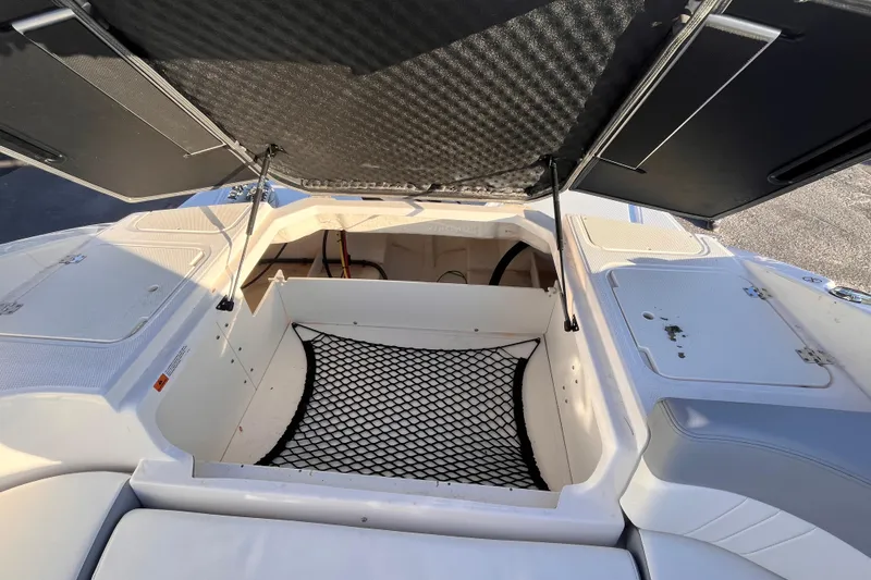 Slide: The Image of 2025 Chaparral 23 SSi OB boat storage compartment with open hatch and netting. - 11