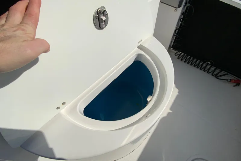 Slide: The Image of 2020 Aquasport 2500 Center Console livewell with open lid and hand for scale. - 20
