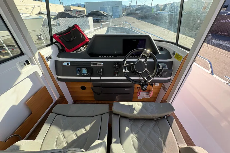 Slide: The Image of 2021 Axopar 28 Cabin boat interior with modern steering console and seating. - 11