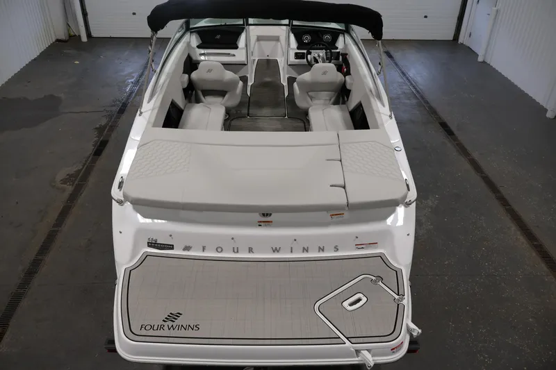 Slide: The Image of 2026 Four Winns H4 Freedom boat interior, showcasing seating and dashboard in a garage setting. - 9