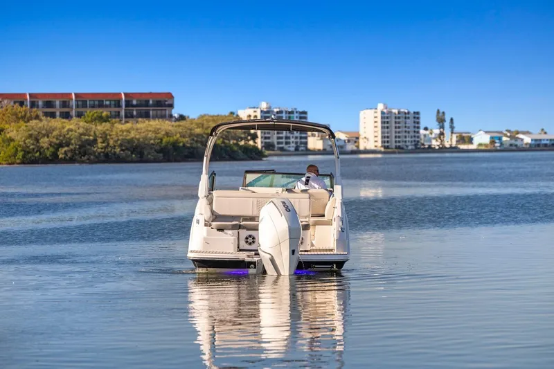 Slide: The Image of 2023 Sea Ray SDX 250 Outboard boat on calm water with cityscape background. - 2