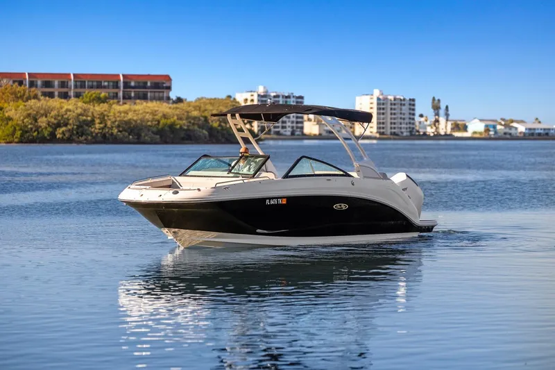 Slide: The Image of 2023 Sea Ray SDX 250 Outboard boat on calm water with cityscape background. - 4