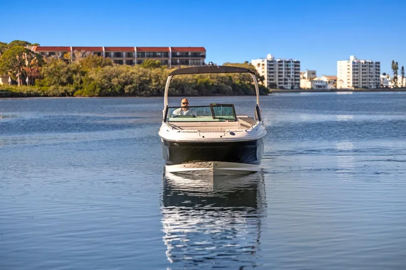 Slide: The Image of 2023 Sea Ray SDX 250 Outboard cruising on a calm lake with cityscape background. - 5