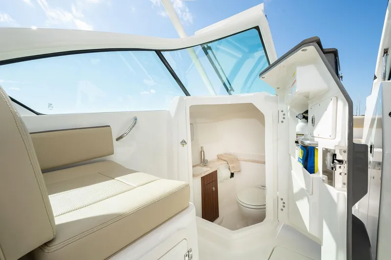 Slide: The Image of 2026 Pursuit DC 266 Dual Console boat interior with seating and compact bathroom. - 11