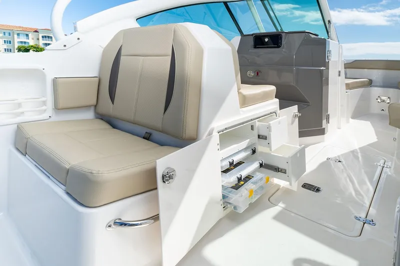 Slide: The Image of 2026 Pursuit DC 266 Dual Console boat interior with beige seating and storage compartments. - 7