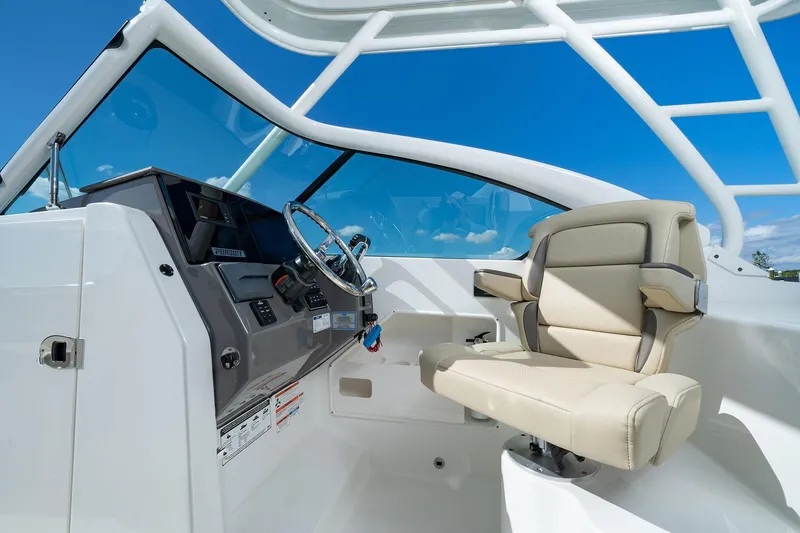 Slide: The Image of 2026 Pursuit DC 266 Dual Console boat interior with steering wheel and beige captain's chair. - 9