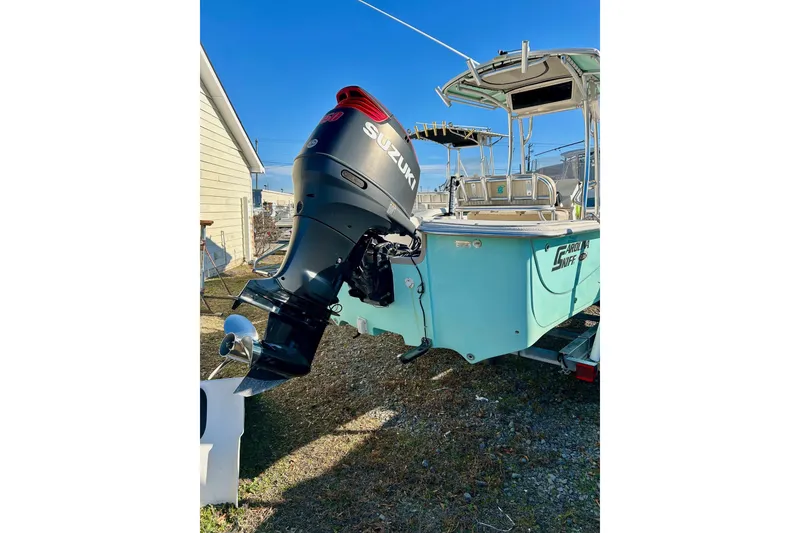 Slide: The Image of 2018 Carolina Skiff 238 DLV with Suzuki outboard motor, parked on grass. - 3