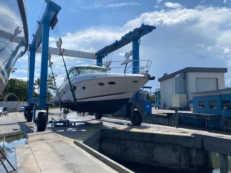 Slide: The Image of 2012 Sea Ray 450 Sundancer yacht being lifted at a marina under a clear blue sky. - 41