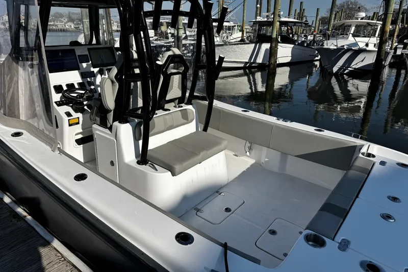 Slide: The Image of 2024 Cape Horn 32 T boat interior with helm, seating, and docked boats in background. - 4