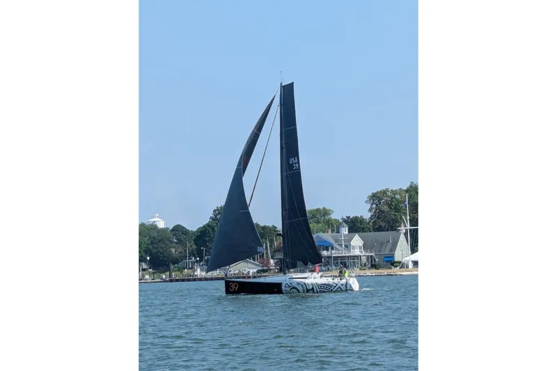 Slide: The Image of Sailboat Class 40 Akilaria 2007 on water near shoreline with buildings in background. - 6