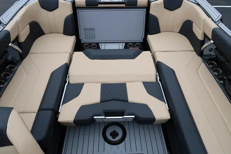 Slide: The Image of 2025 MasterCraft XT22 boat interior with beige and black seating, cup holders, and sleek design. - 17