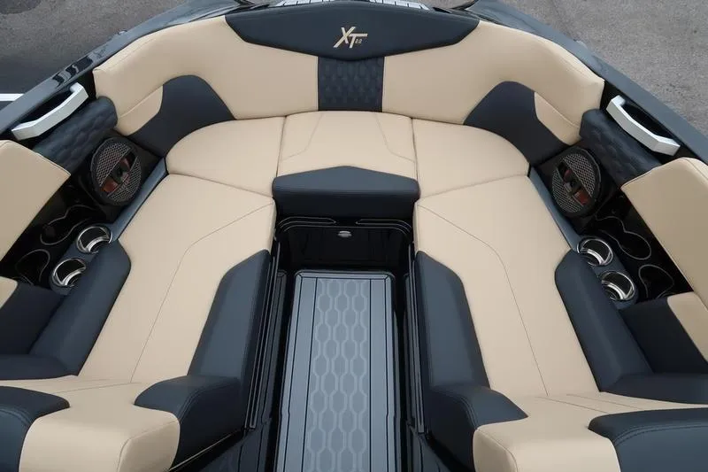 Slide: The Image of 2025 MasterCraft XT22 boat interior with beige and black seating, cup holders, and speakers. - 44