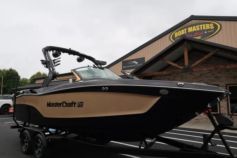 Slide: The Image of 2025 MasterCraft XT22 boat on trailer at dealership, overcast day. - 5