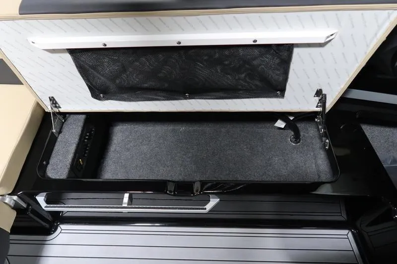 Slide: The Image of 2025 MasterCraft XT22 boat storage compartment with open lid and netted pocket. - 57