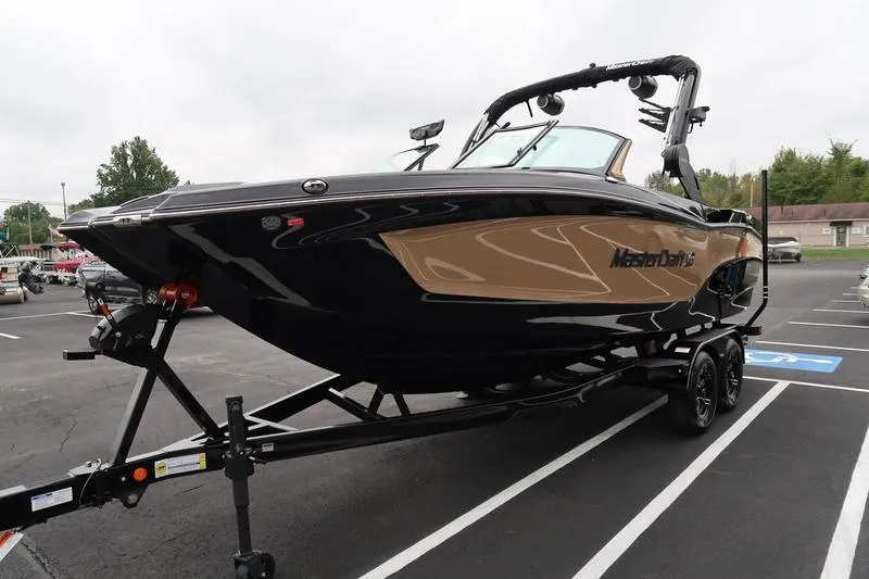 Slide: The Image of 2025 MasterCraft XT22 boat on trailer in parking lot. - 6
