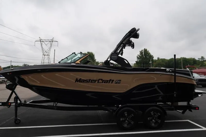 Slide: The Image of 2025 MasterCraft XT22 boat on trailer, parked outdoors on a cloudy day. - 7
