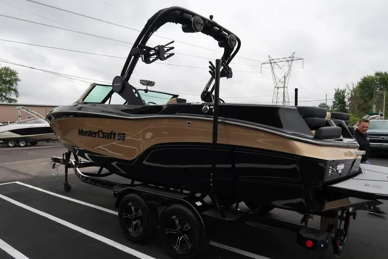 Slide: The Image of 2025 MasterCraft XT22 boat on trailer, black and gold design, parked outdoors. - 9