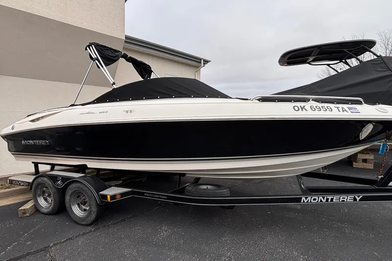 The Image of 2006 Monterey 228SI Montura Bowrider on trailer, black and white design, covered and parked. - 1