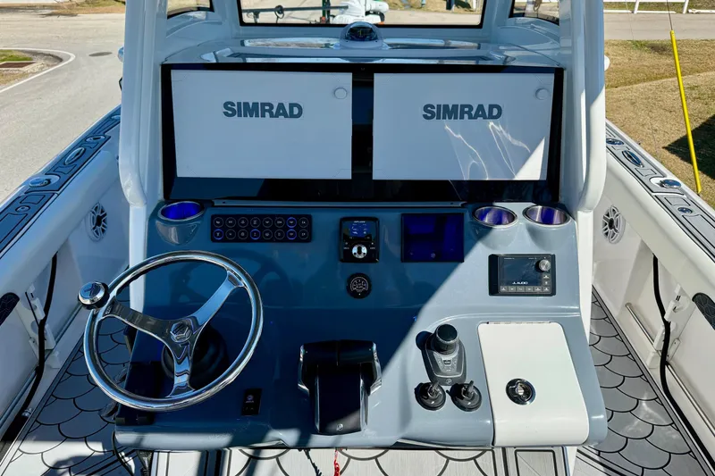 Slide: The Image of 2024 Tidewater 3100 Carolina Bay boat dashboard with dual Simrad displays and modern controls. - 11