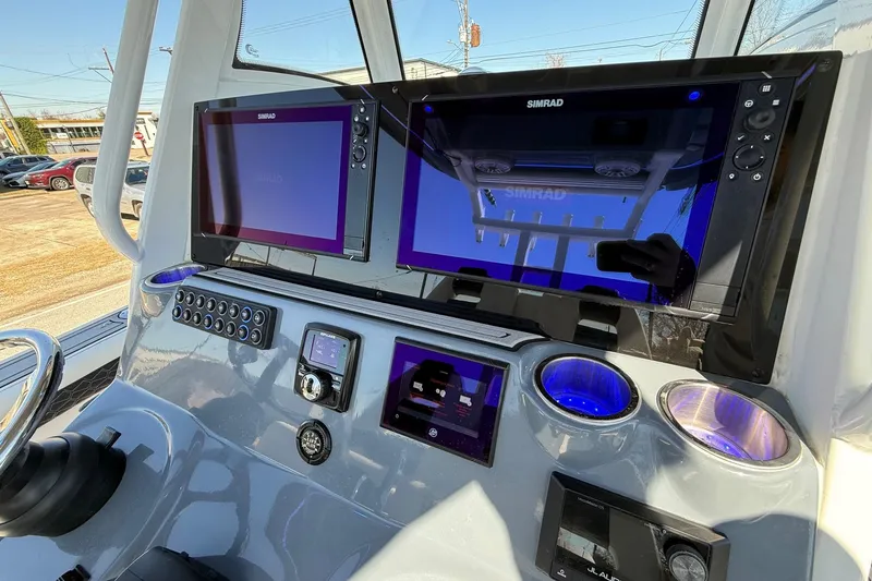 Slide: The Image of 2024 Tidewater 3100 Carolina Bay boat dashboard with dual Simrad displays and controls. - 18