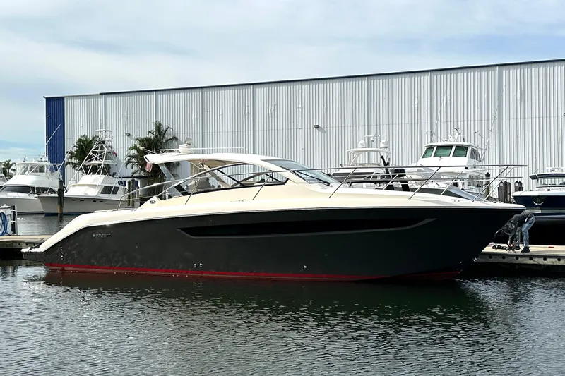 The Image of 2014 Pursuit SC 365i Sport Coupe docked at marina, sleek design, calm water. - 1