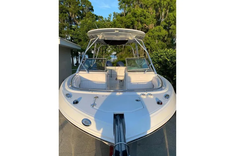 Slide: The Image of 2015 Robalo R247 Dual Console boat, white exterior, parked outdoors with lush greenery. - 3