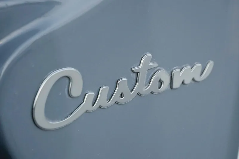 Slide: The Image of "Custom" emblem on 2026 Tidewater 282 CC Adventure boat, sleek gray finish. - 22