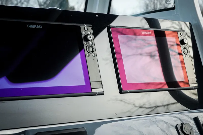 Slide: The Image of Simrad displays on 2026 Tidewater 282 CC Adventure boat dashboard, reflecting sky. - 54