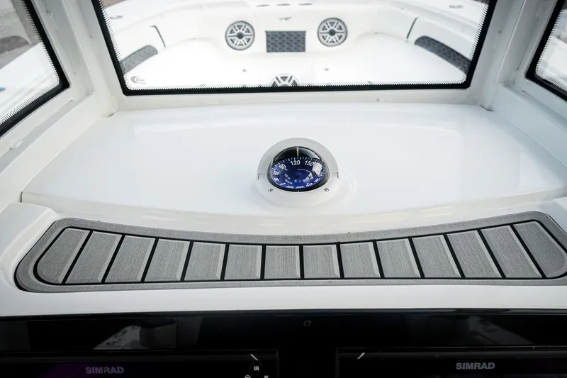 Slide: The Image of 2026 Tidewater 282 CC Adventure boat dashboard with compass and Simrad display. - 63